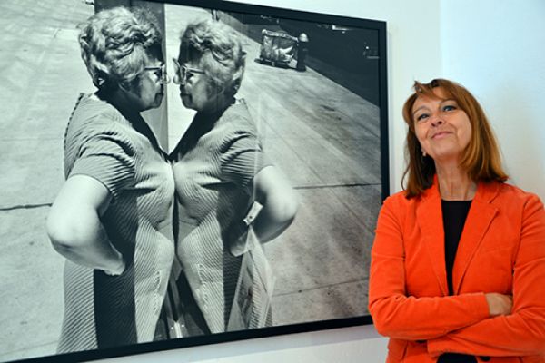 Die Leiterin des KuK Monschau, Frau Dr. Nina Mika-Helfmeier, neben dem Foto von Richard Kalvar „Woman looking at herself in store window, New York City, 1969“